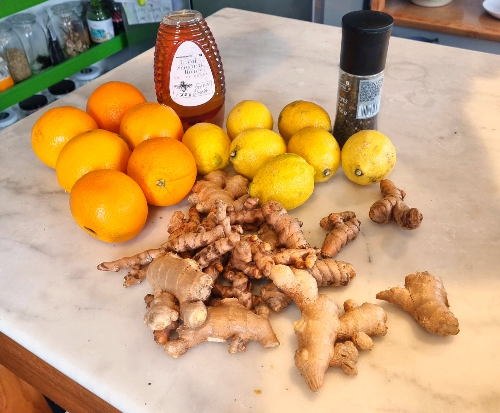 Fresh oranges, lemons, ginger, turmeric, honey and black pepper on a kitchen counter